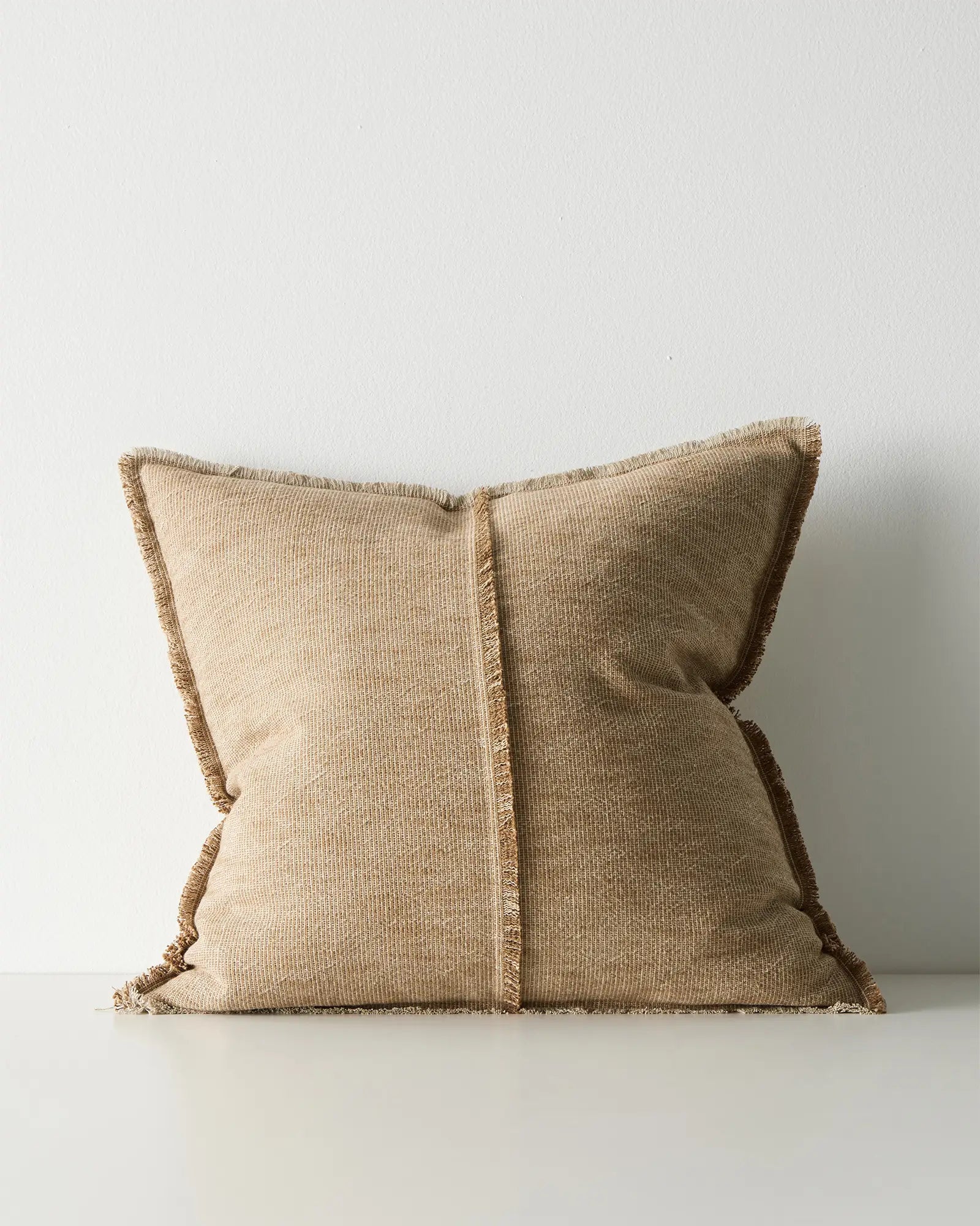 Beige pillow with frayed edges.