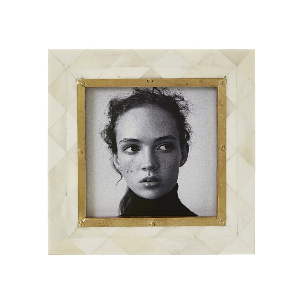 Framed black and white portrait with a decorative gold frame on a textured beige background