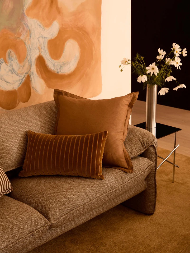 pin stripe cushion made from velvet is a warm orange tone.