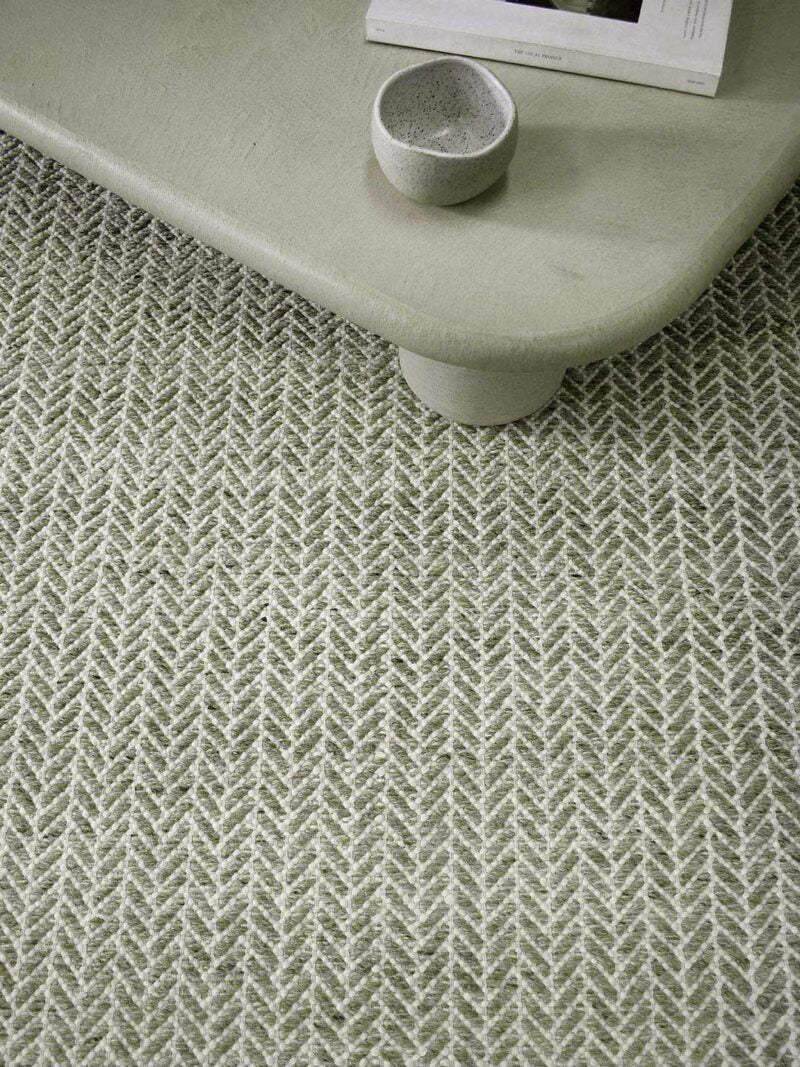 Textured green rug with a arrow pattern.