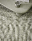 Textured green rug with a arrow pattern.