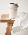Gili is a shorter ivory coloured linear vase, with its compact design, radiates contemporary charm. Its modest height adds versatility, making it an ideal vessel for smaller arrangements. Ribbed detail and ivory colour.