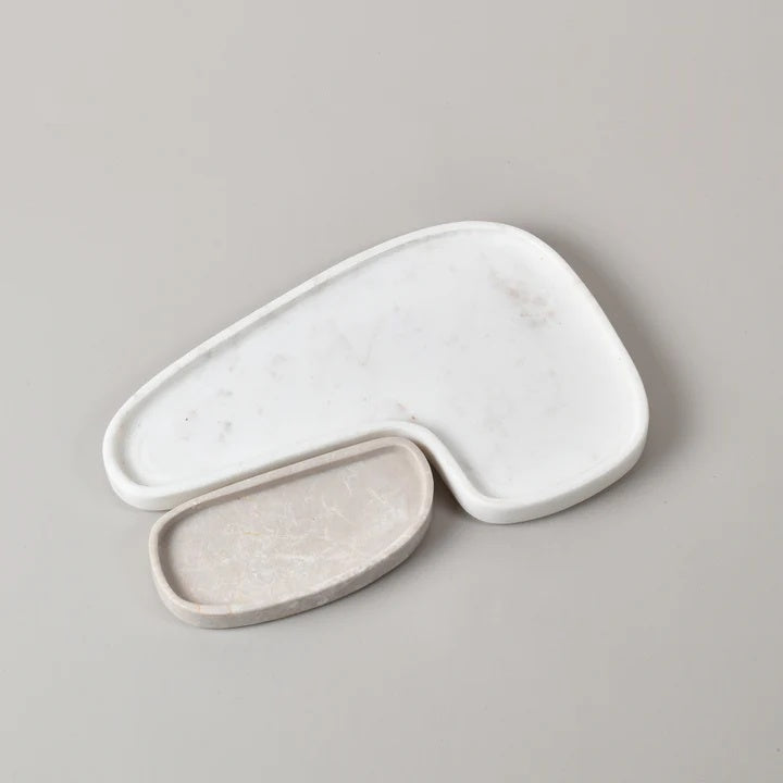 Compromising of two organic shaped trays that pair together to create a decorative and sculptural place to display jewellery and other trinkets. White and beige marble organic shaped trays.