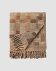 Woven blanket with a checkered pattern and fringes on a light beige background