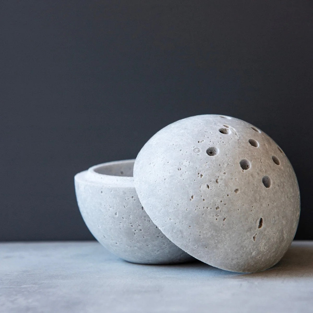 A white travertine sphere, crafted in two perfectly balanced halves. Designed with small holes at the top, it allows incense smoke to drift gently, creating a calming, ethereal effect.