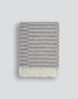 Gray striped blanket with white fringe on a light gray background