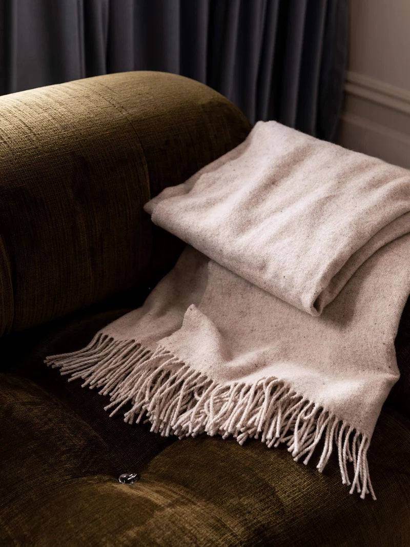 Beige blanket with fringing. 
