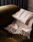 Beige blanket with fringing. 