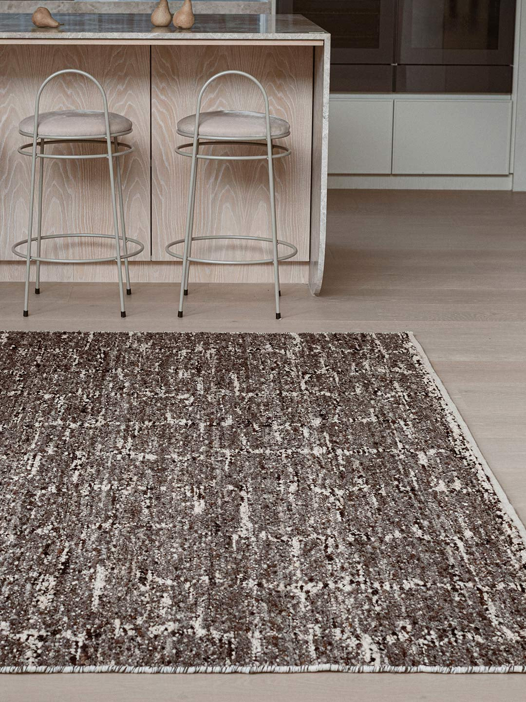 Patterned rug on a wooden floor with brown ivory tones
