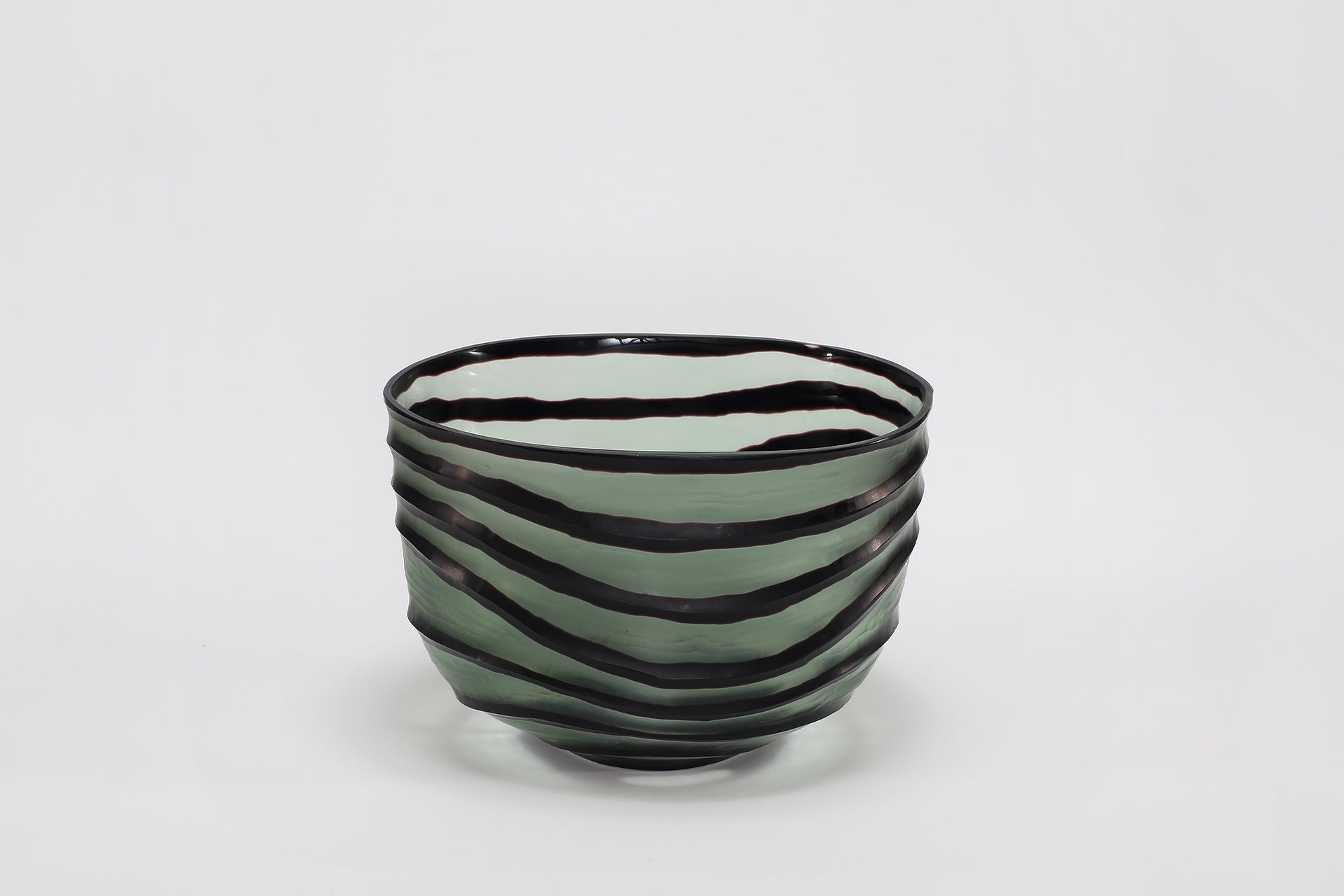 Green glass bowl with black stripes and an irregular shape.