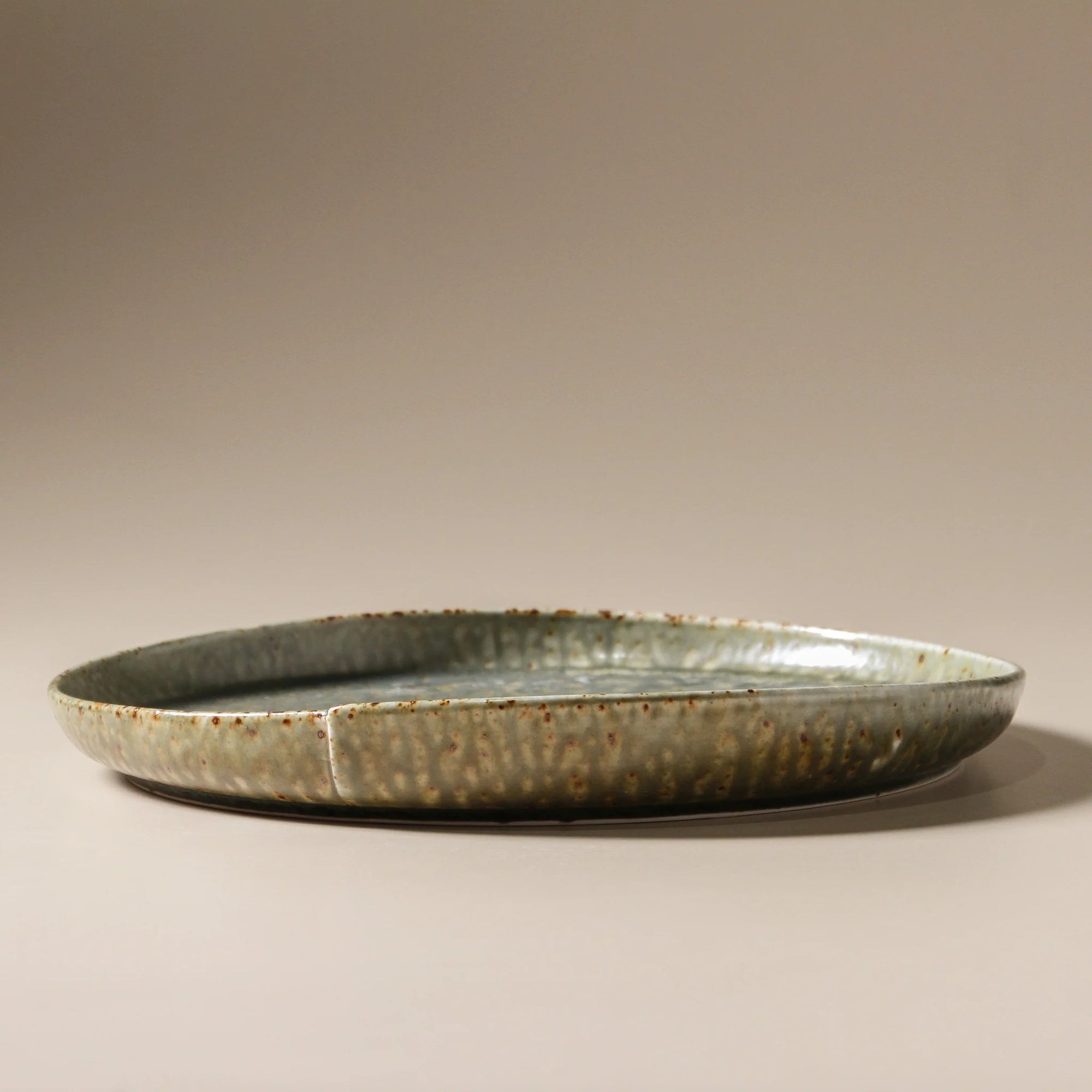 Ceramic plate with a textured surface on a beige and green glaze  background