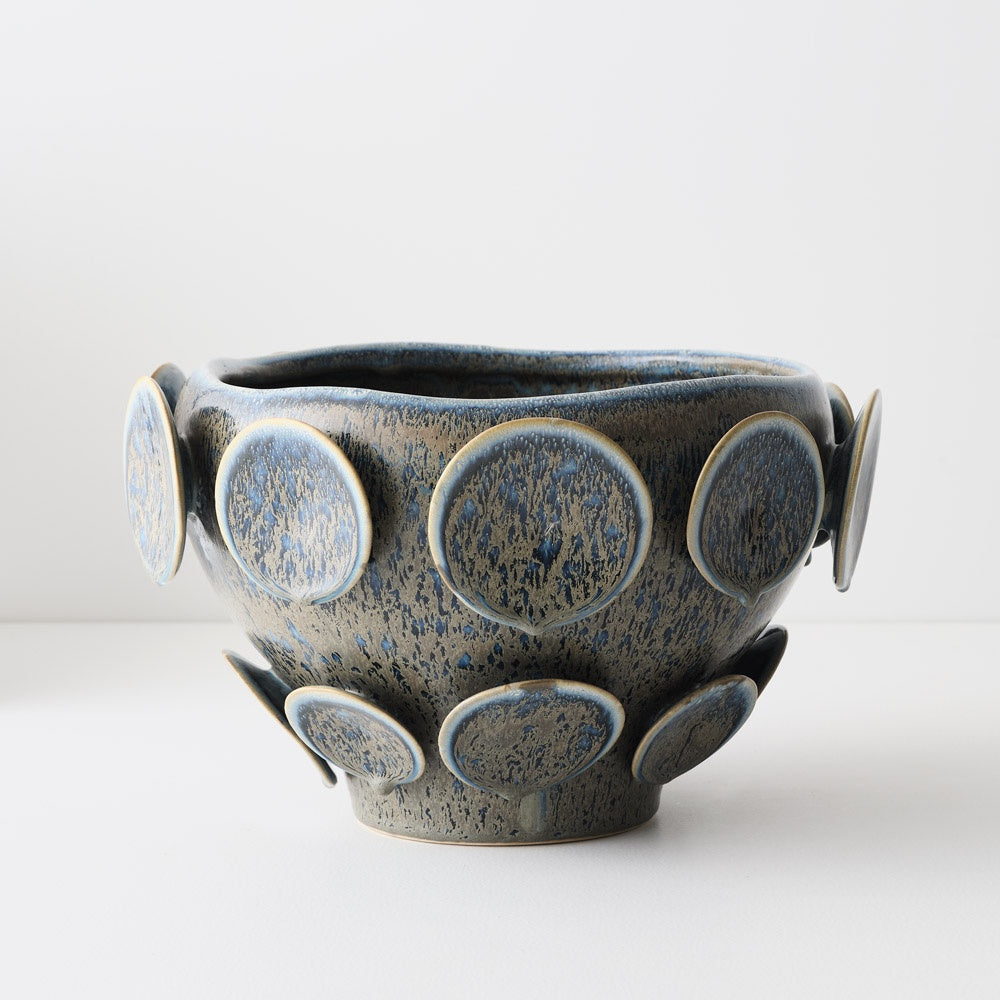 Ceramic bowl with circular patterns with a blue green glaze.