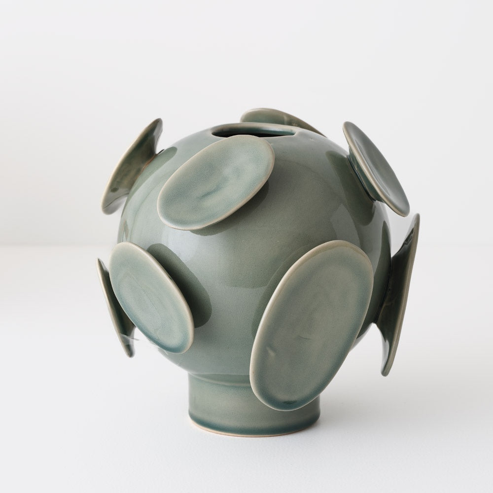 Green ceramic vase with circular protrusions and a shiny gklaze.
