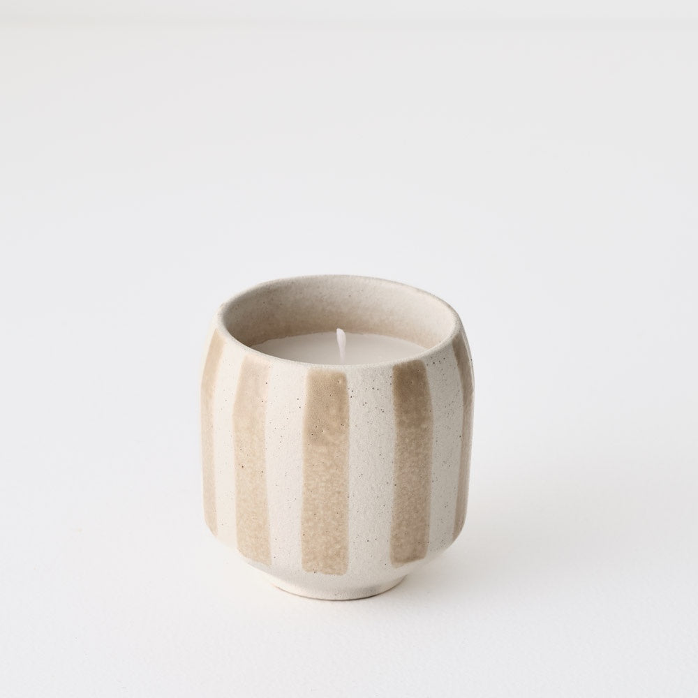 Ceramic striped candle holder with a candle inside . beige and white 