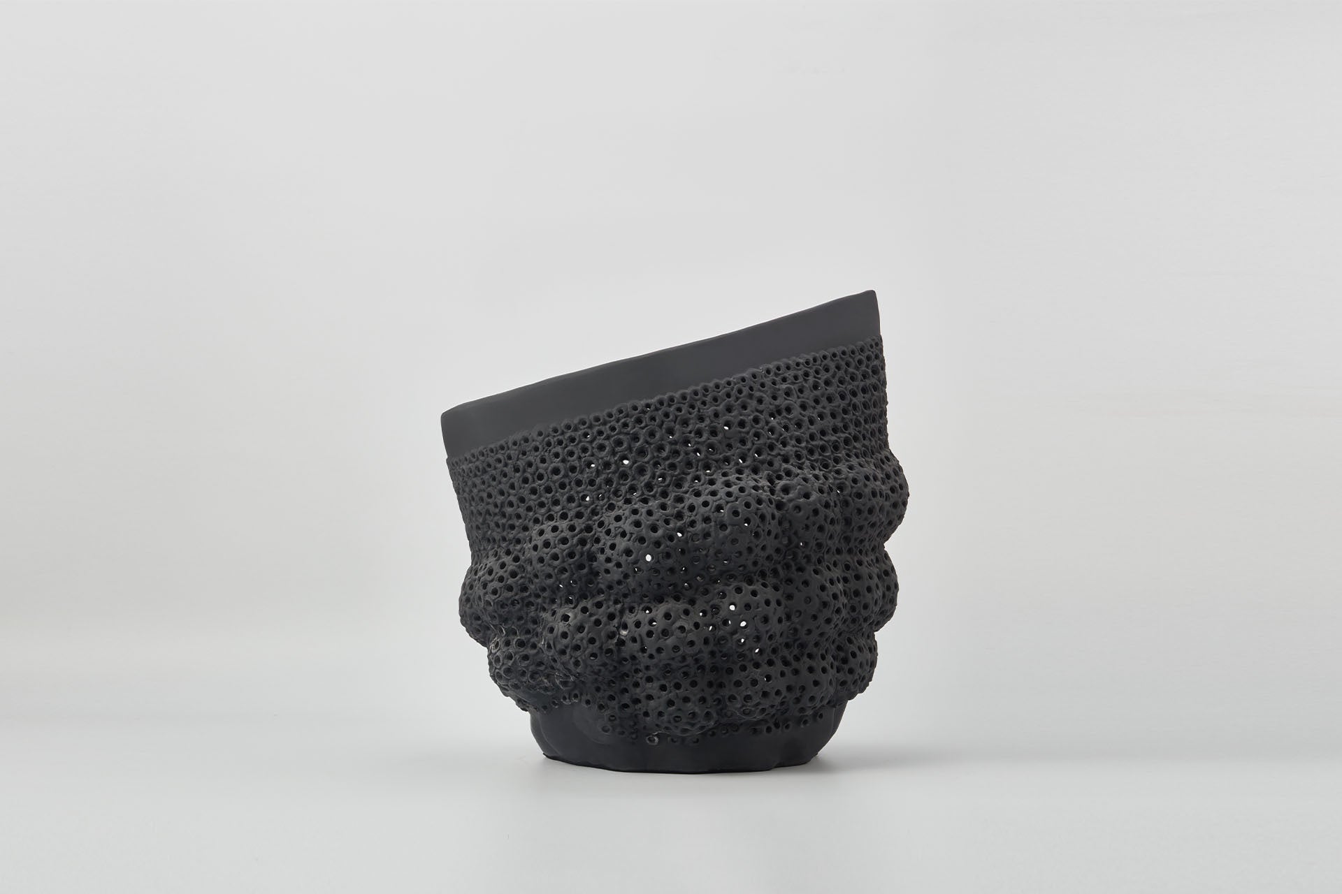 Black textured vase with perforated holes and bulbous shapes.