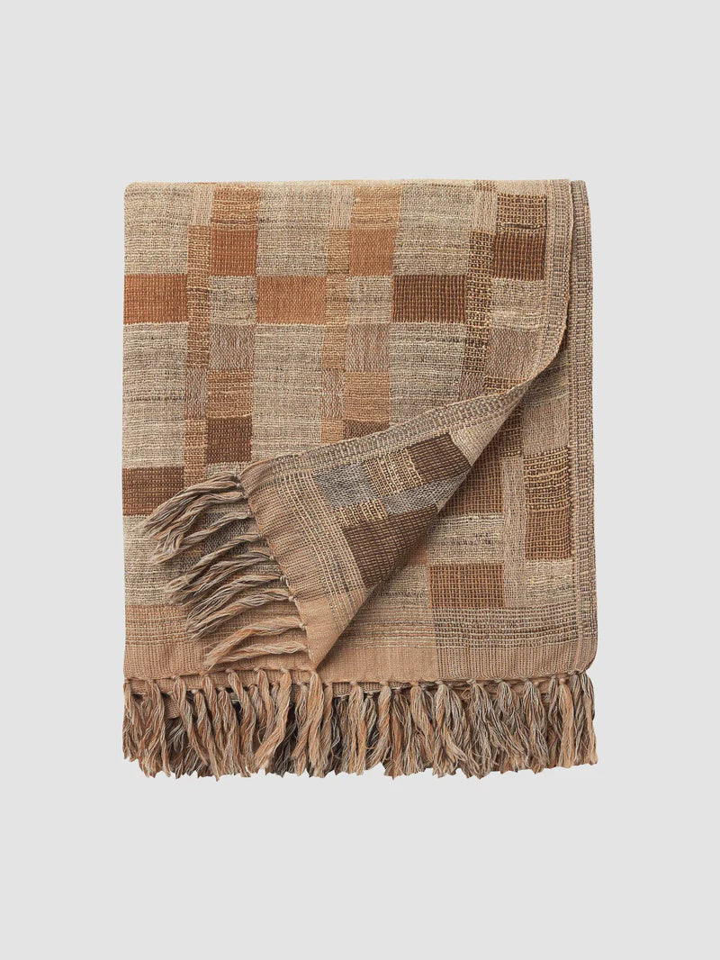 Woven blanket with a checkered pattern and fringes on a light beige background