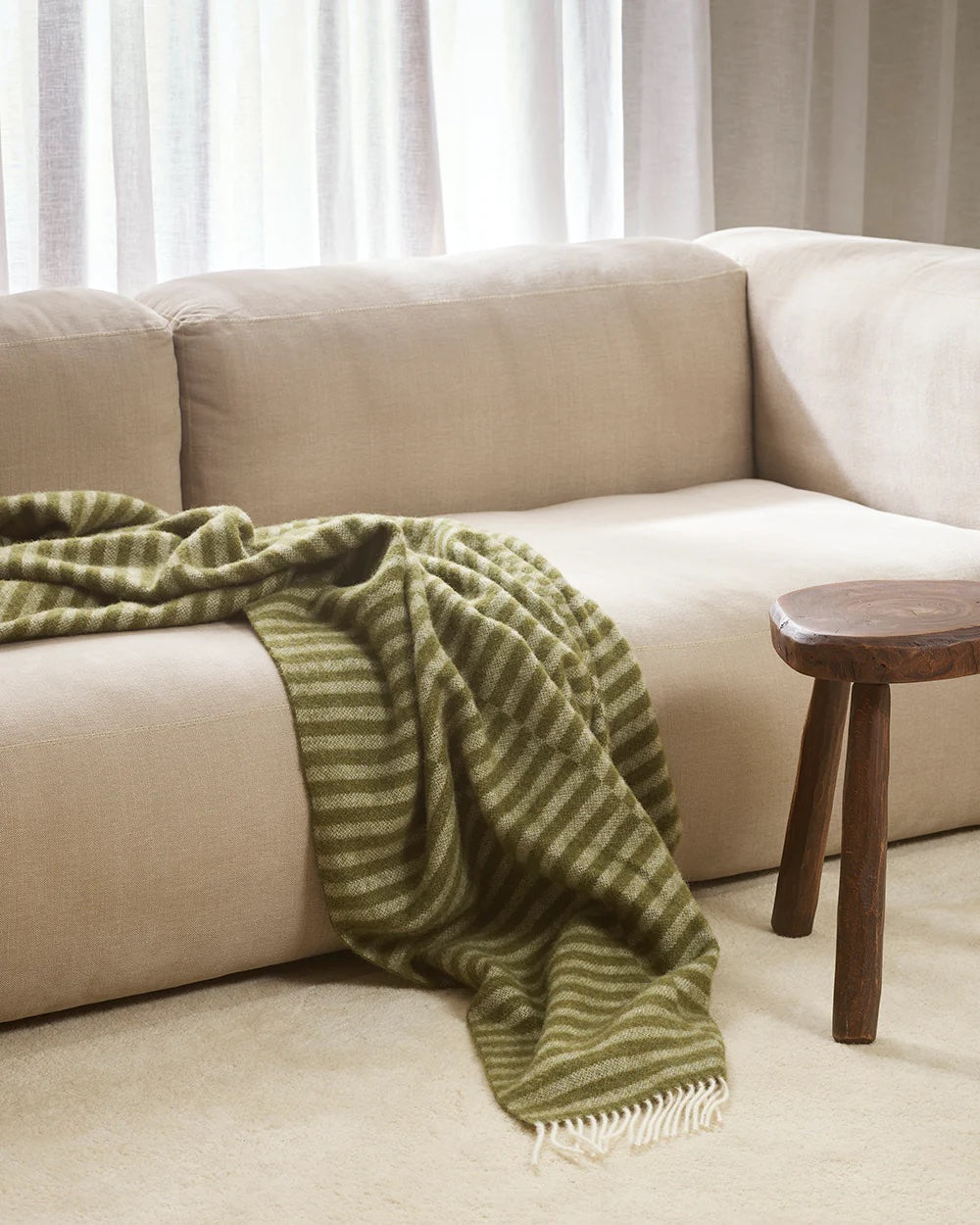 olive green striped blanket with white fringe

